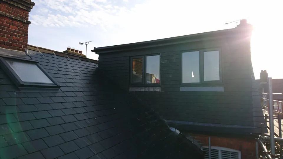 Slate-clad rear dormer with windows in the afternoon sun