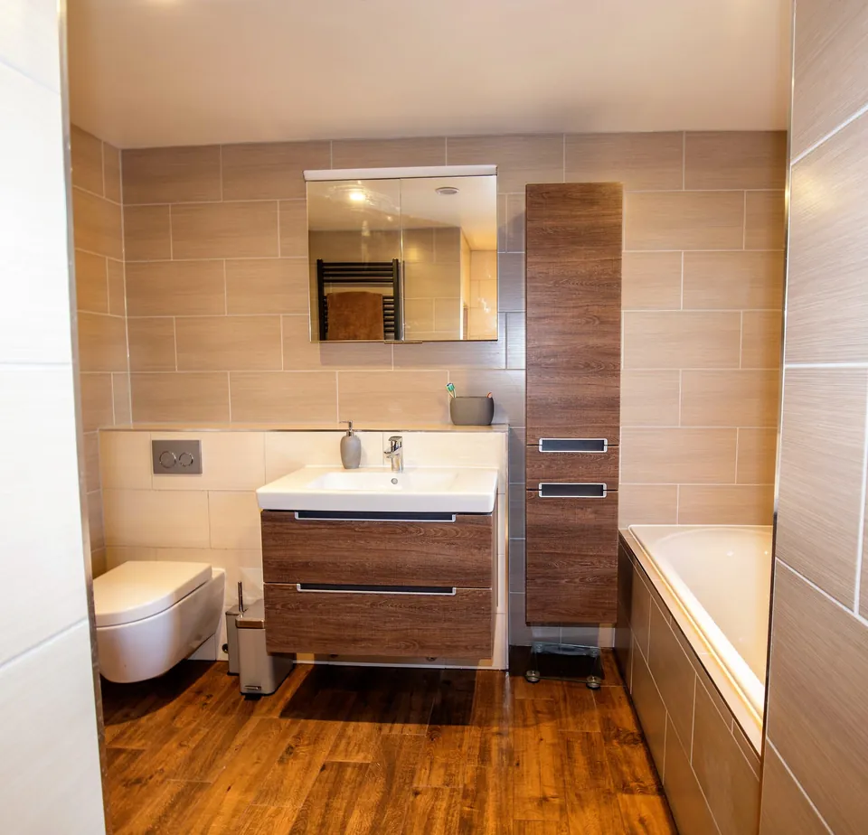 Ensuite bathroom with walnut-effect vanity unit and bath