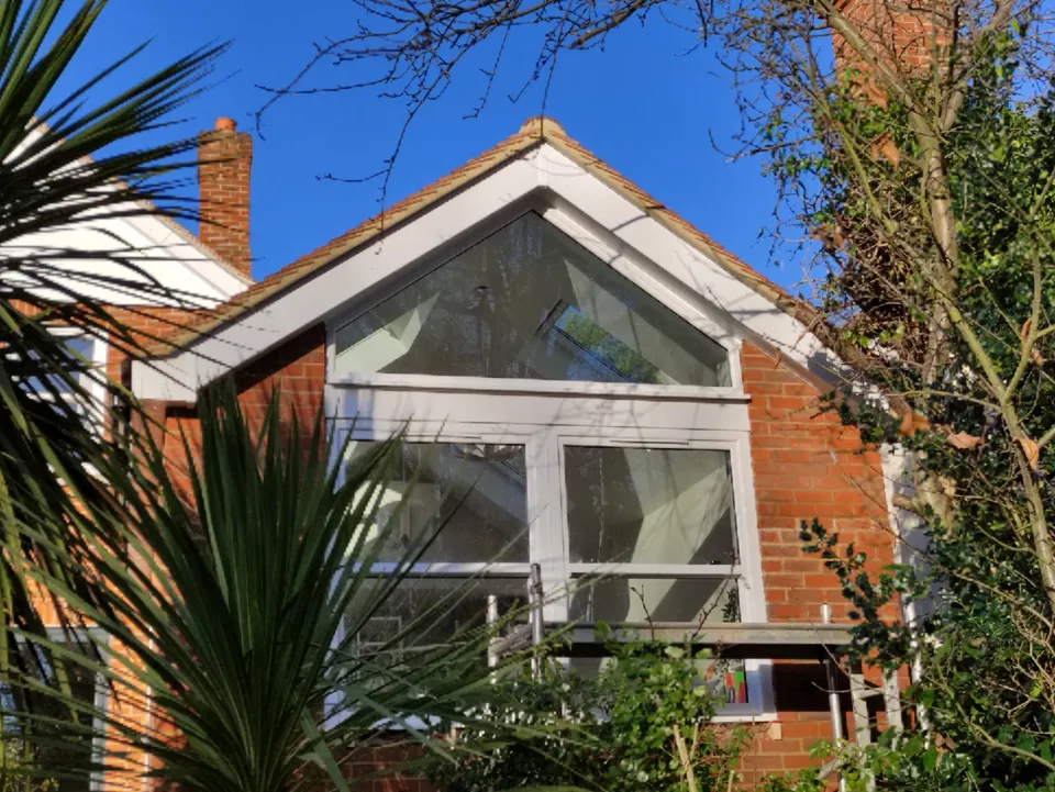 Gable-end loft conversion with a large glazed window above a brick house