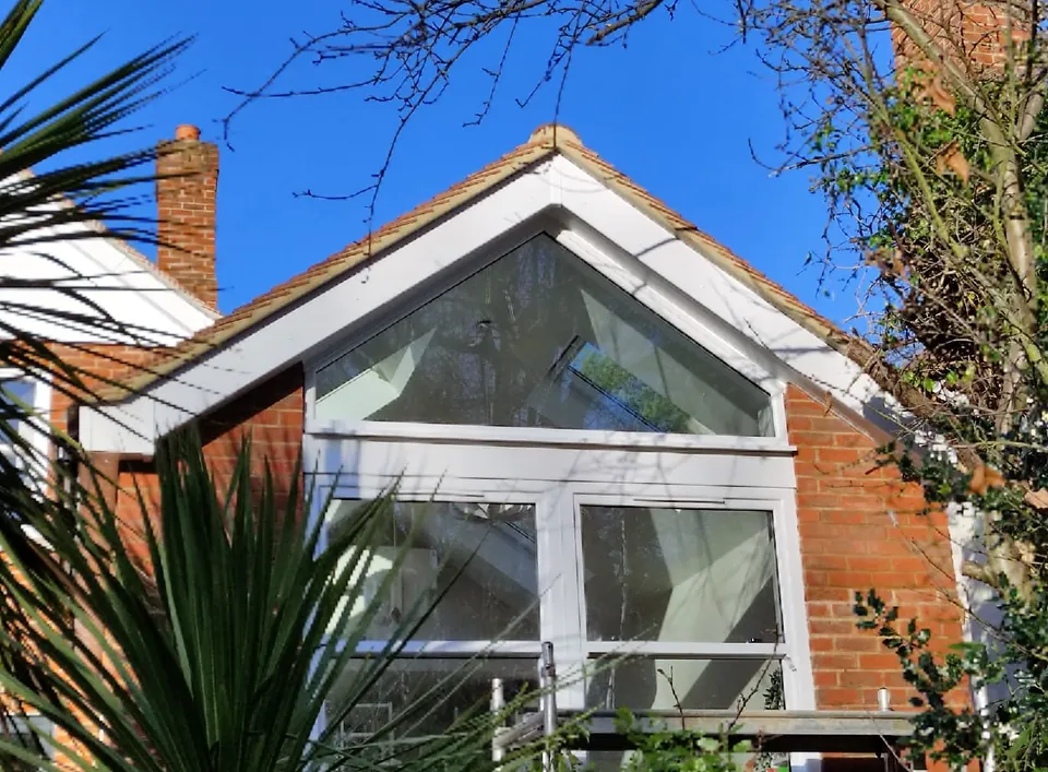 Gable-end loft conversion with a large triangular window above a brick home