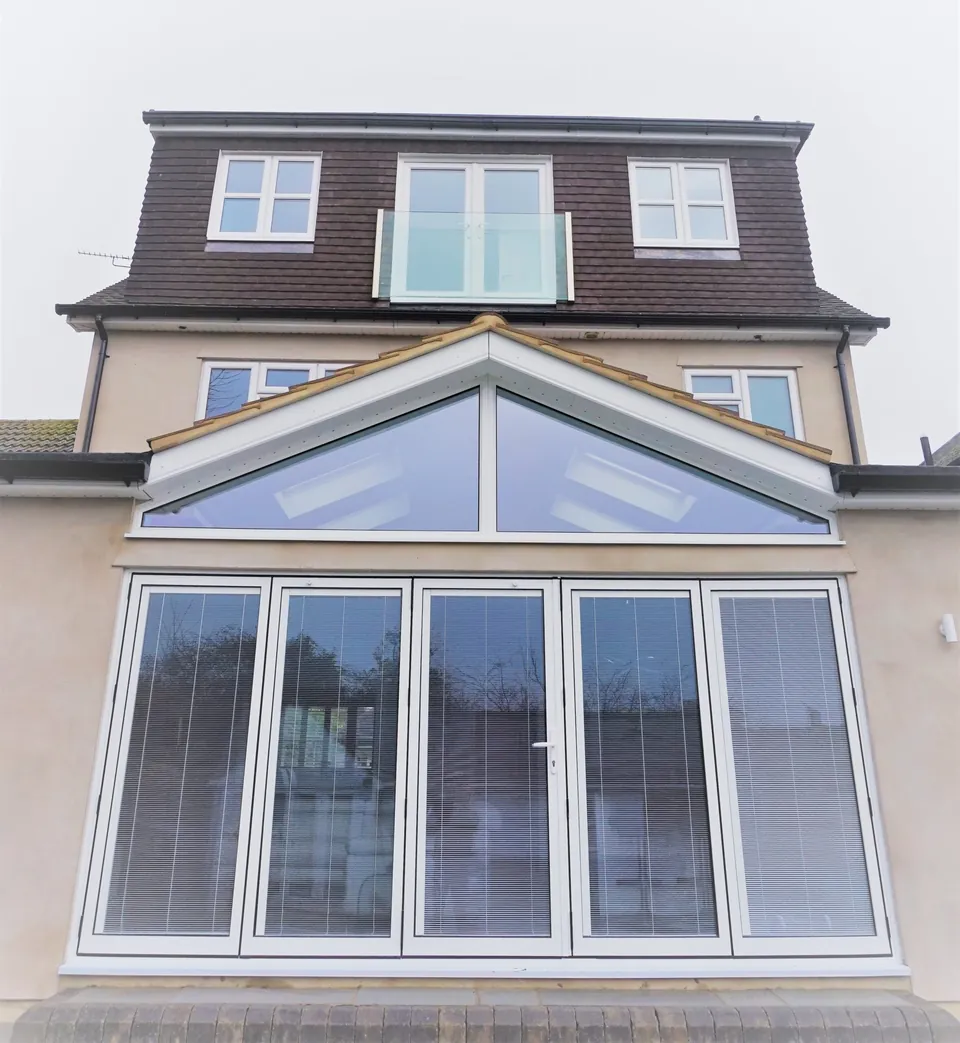 Glazed gable and bi-fold doors beneath a rear dormer with glass balcony