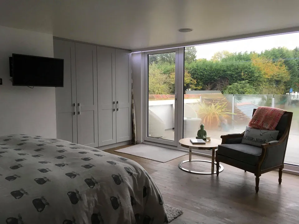 Converted loft master bedroom with fitted wardrobes and glazed doors to a terrace